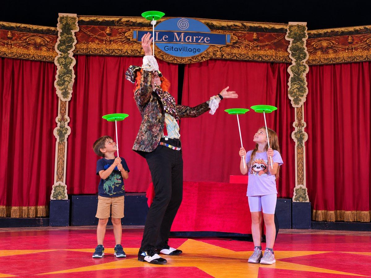 Artista di circo insegna a due bambini a far girare i piatti cinesi sulla pista del villaggio